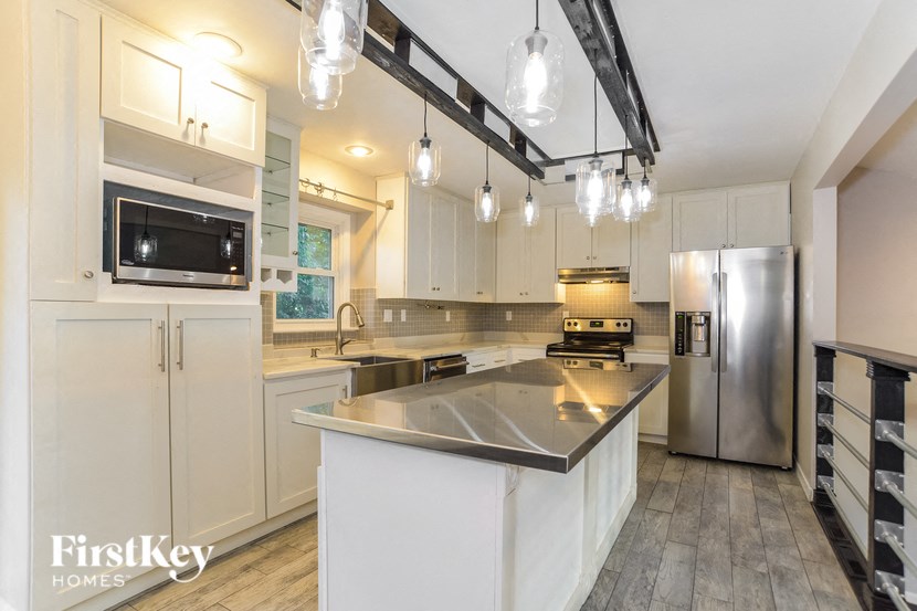 A kitchen with a stainless steel island and white cabinets.