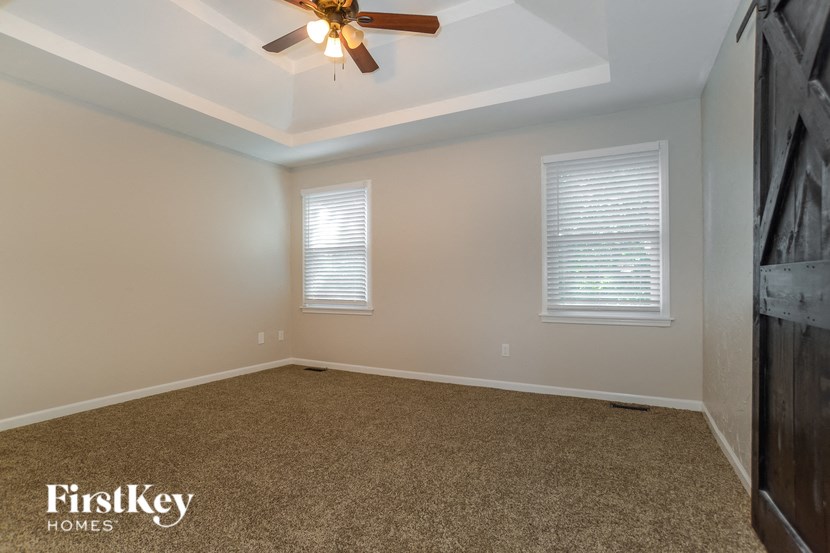 A room with a ceiling fan and two windows.