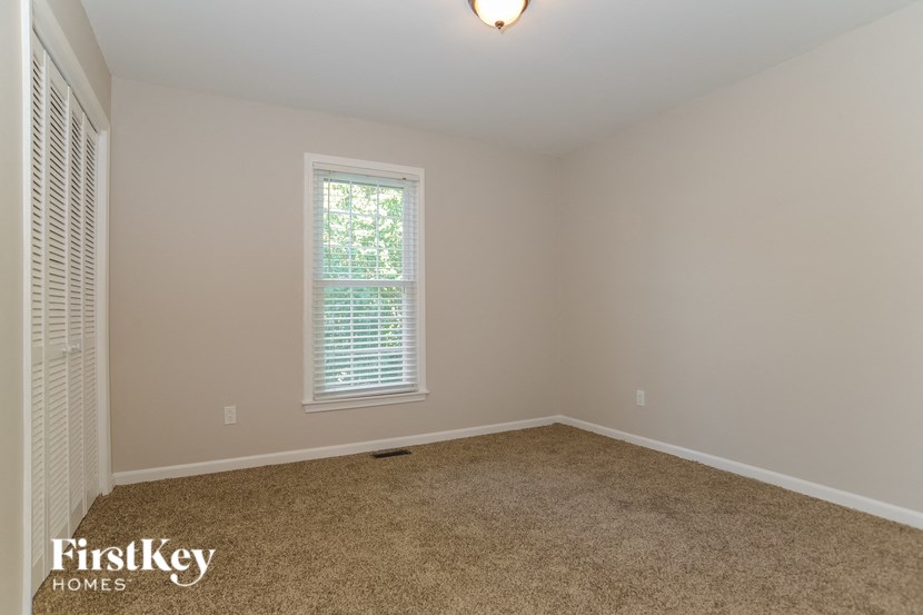 A room with a window and a carpeted floor.