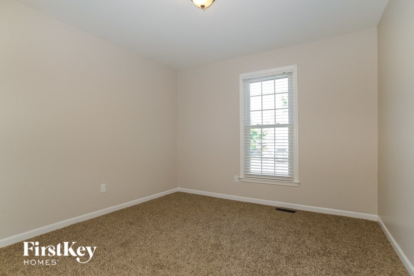 A room with a carpeted floor and a window with blinds.