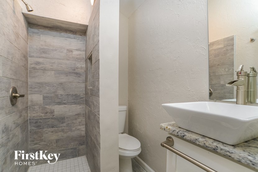 A bathroom with a marble counter top and a walk in shower.