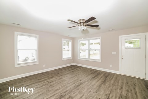 A spacious room with a ceiling fan and wooden flooring.