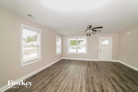 A spacious room with a ceiling fan and wooden flooring.