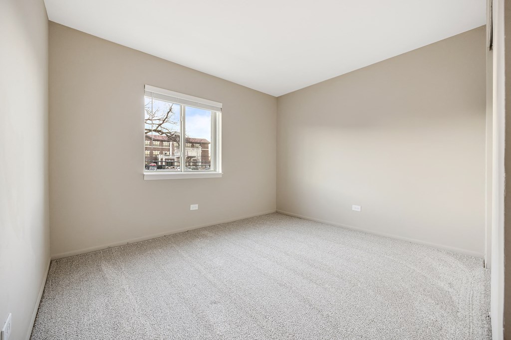 an empty room with a window and carpet