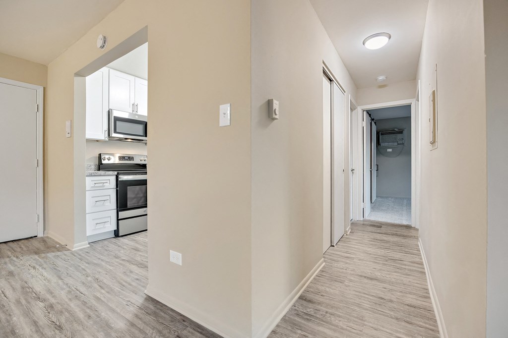 an empty corridor with a kitchen and a hallway leading to a door