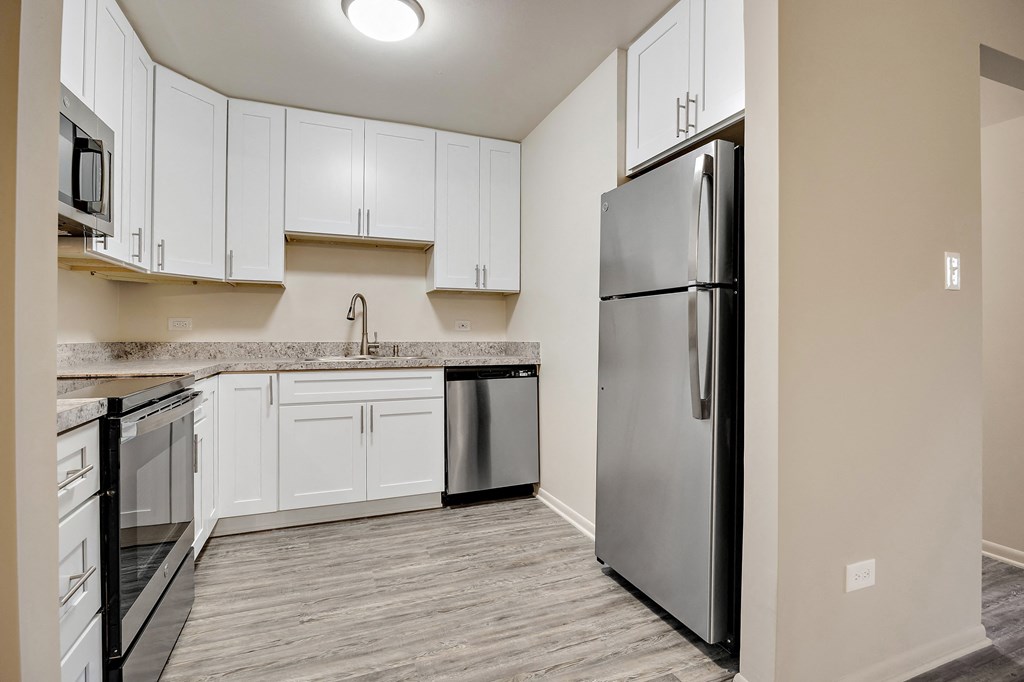 an empty kitchen with white cabinets and a stainless steel refrigerator