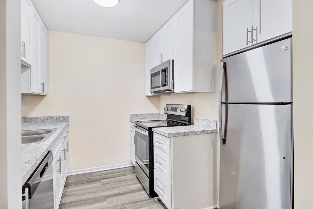 an empty kitchen with white cabinets and stainless steel appliances