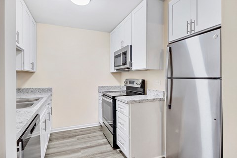an empty kitchen with white cabinets and stainless steel appliances