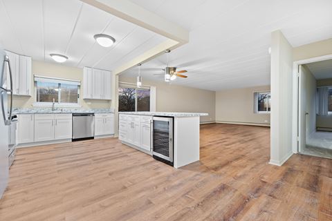 a kitchen and living room with white cabinets and wood floors
