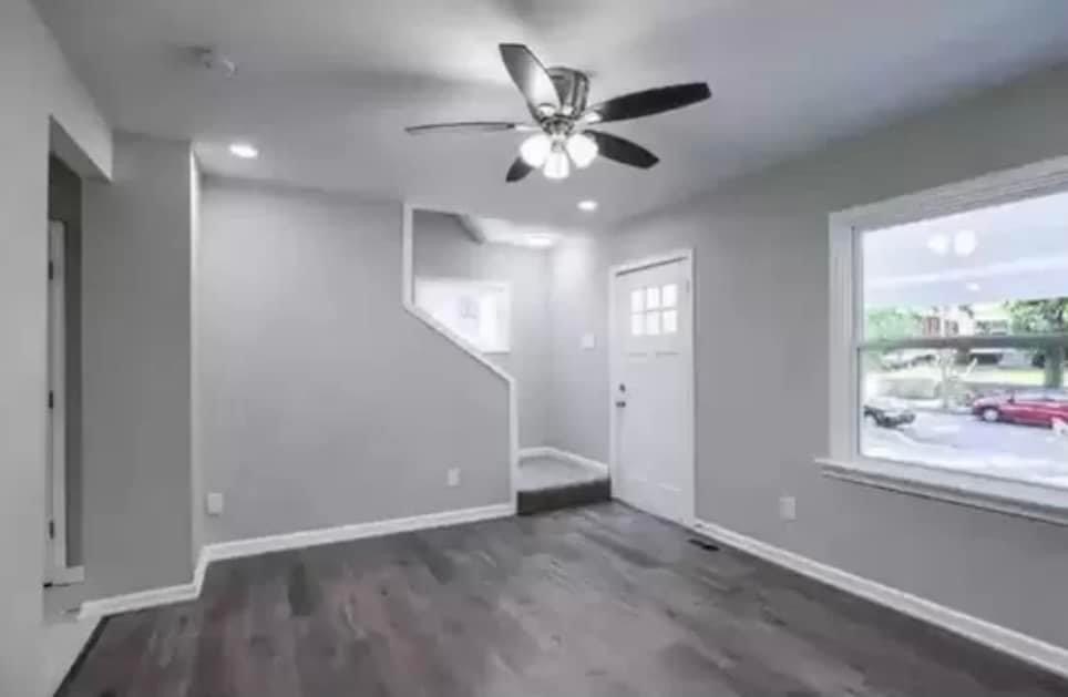 an empty living room with a ceiling fan and a window