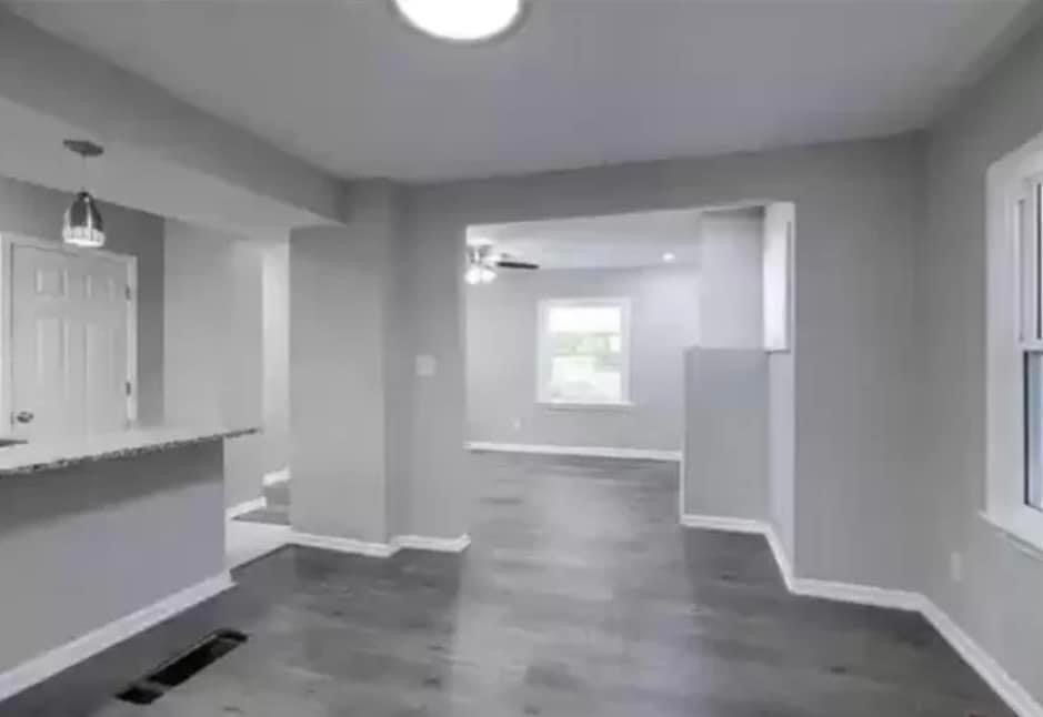 an empty living room with white walls and a kitchen