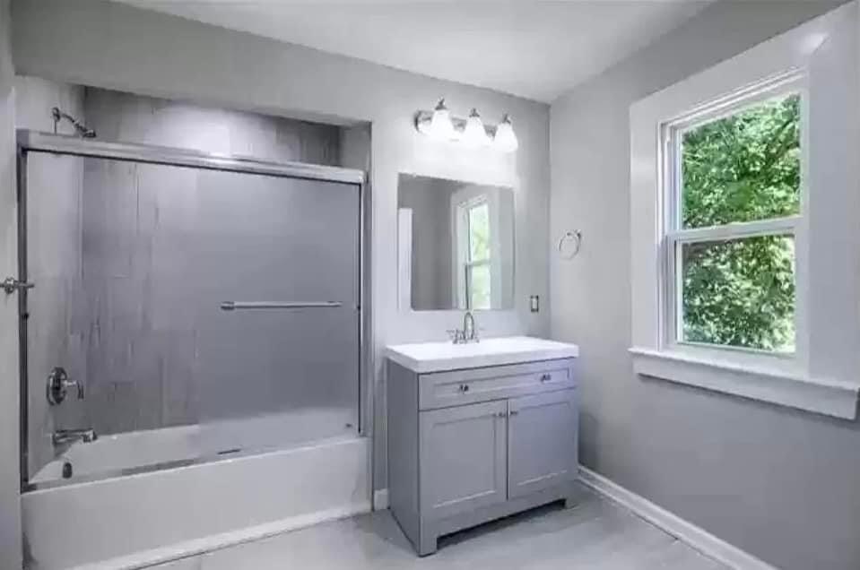 a white bathroom with a tub and a sink and a mirror