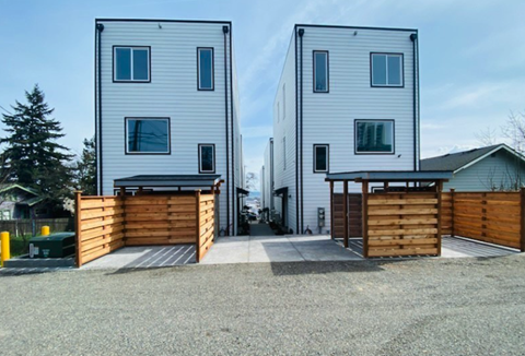 a view of two houses with a wood fence and a sidewalk