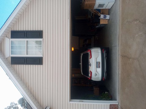 A white car is parked in a garage attached to a house.