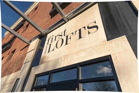 A building with a sign that says "First Lofts".