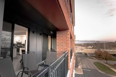 A balcony with a table and chairs overlooks a street.
