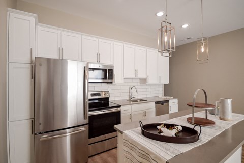 A modern kitchen with a stainless steel refrigerator and white cabinets.