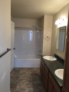 A bathroom with a sink, mirror, and shower.