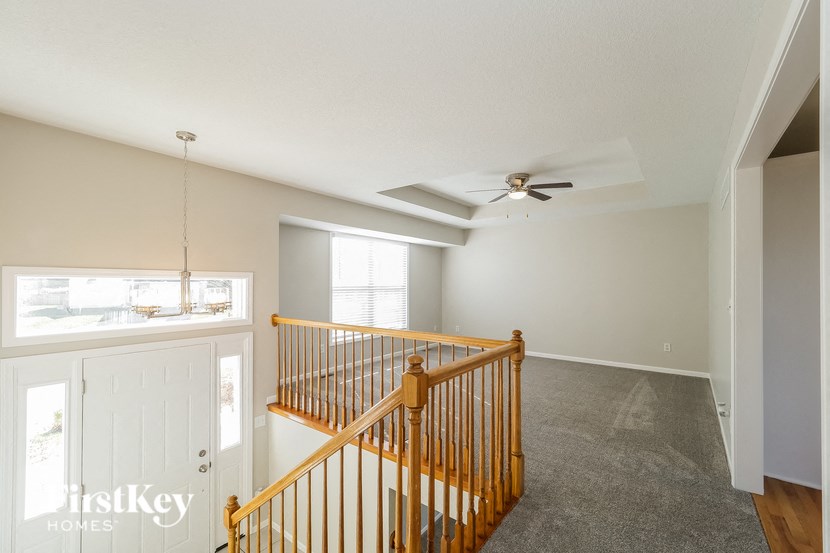 A room with a ceiling fan and a staircase.