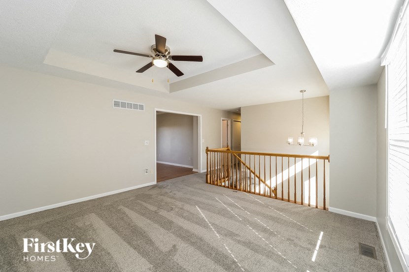 A spacious room with a ceiling fan and a carpeted floor.
