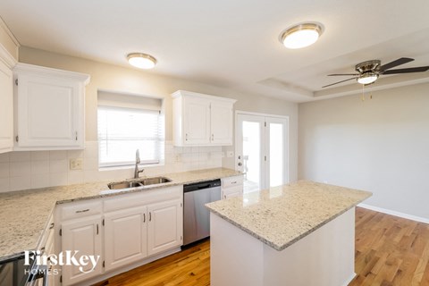 A kitchen with white cabinets and a granite countertop.
