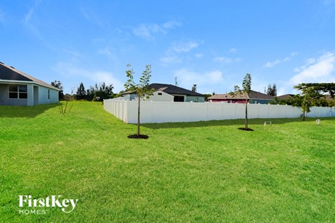 the backyard of a house with two trees and a fence