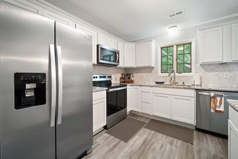 A modern kitchen with a stainless steel refrigerator and white cabinets.