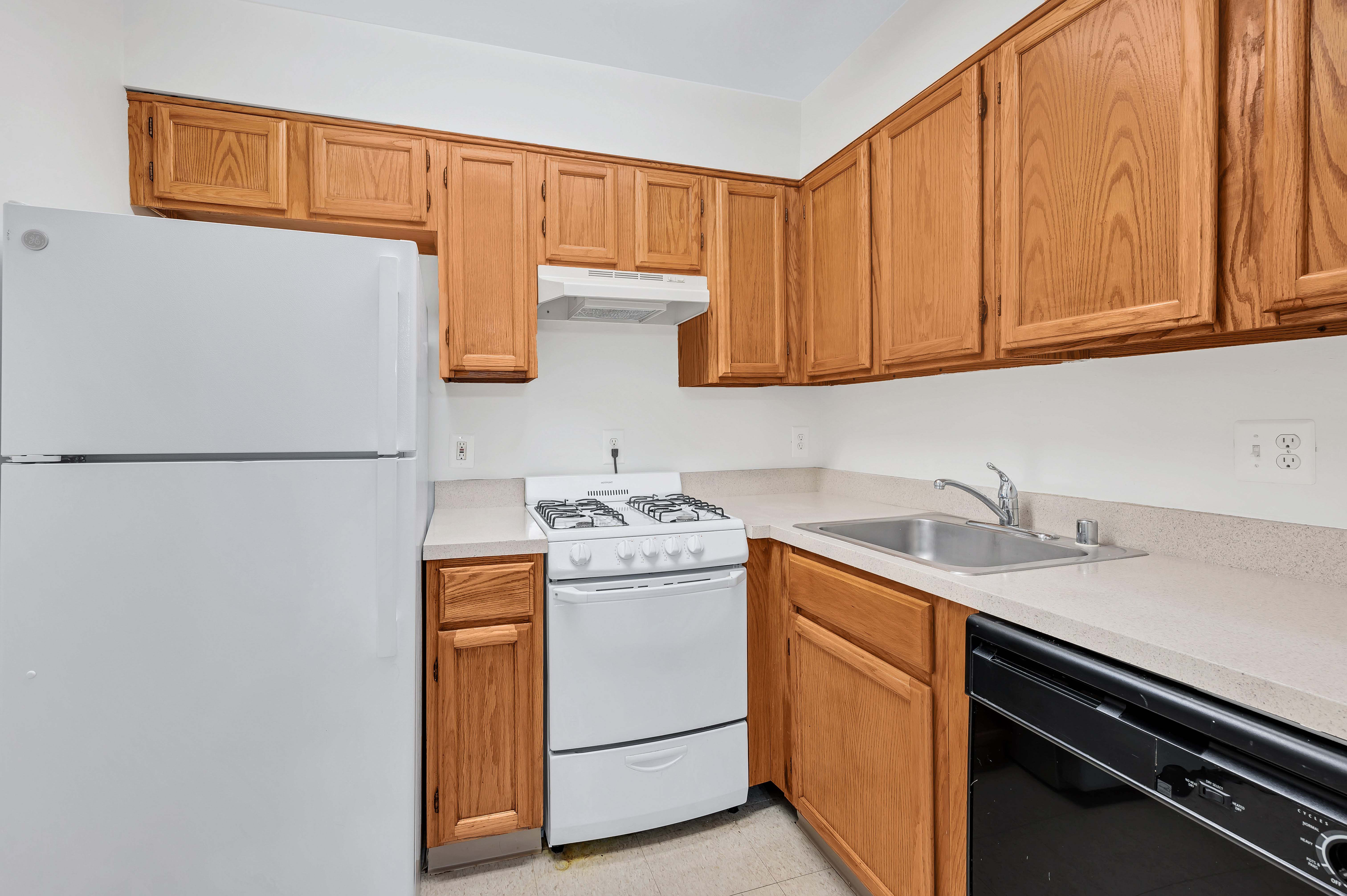 A kitchen with wooden cabinets and a white refrigerator.