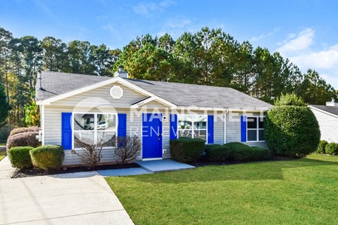 a small white house with blue doors and a lawn