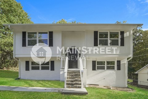 a white house with a staircase in front of a lawn
