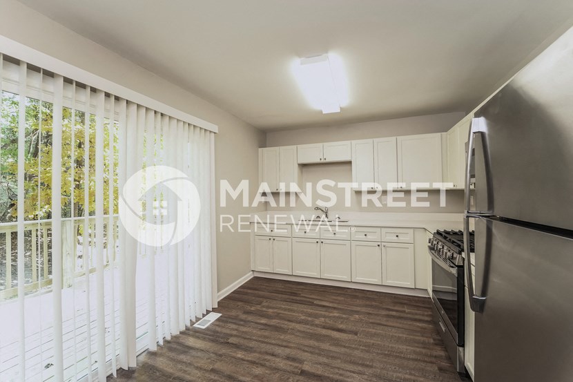 a kitchen with white cabinets and stainless steel appliances and a large window