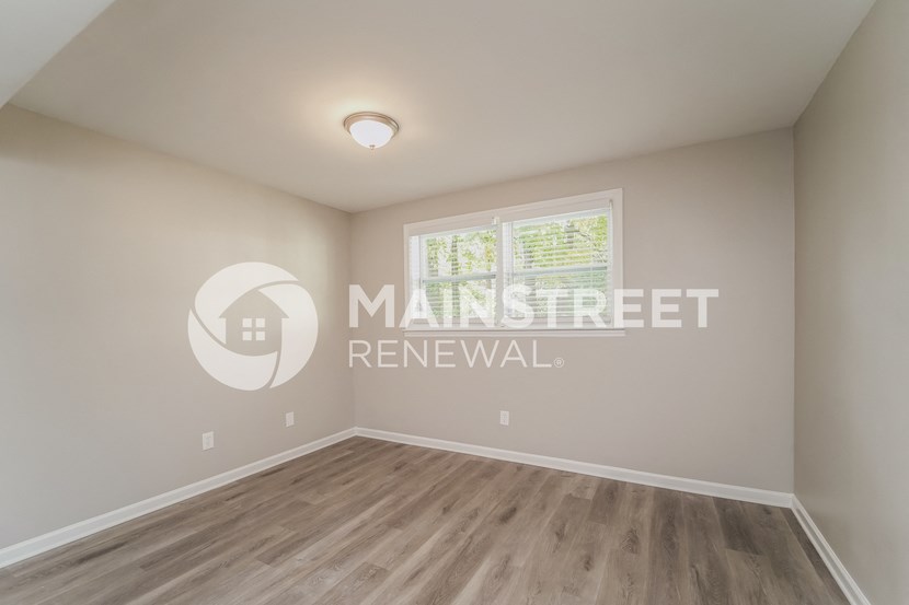 a bedroom with a hardwood floor and a window