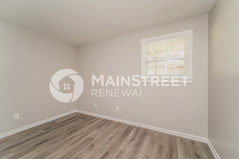 renovated room with hardwood flooring and a window