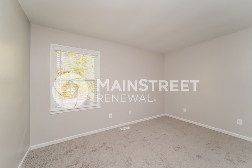 a bedroom with a window and a carpeted floor