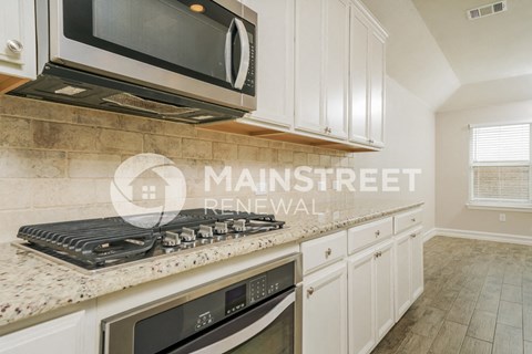 a kitchen with white cabinets and granite counter tops and a stove and microwave