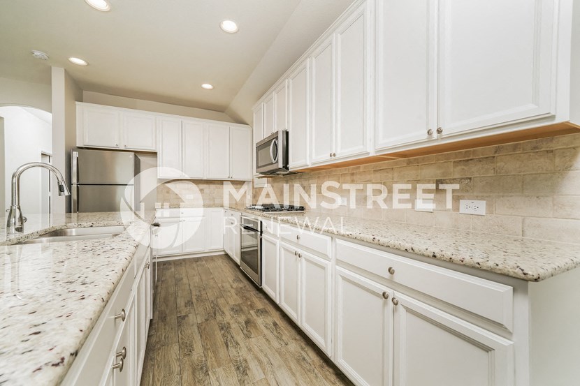 a white kitchen with marble counter tops and white cabinets
