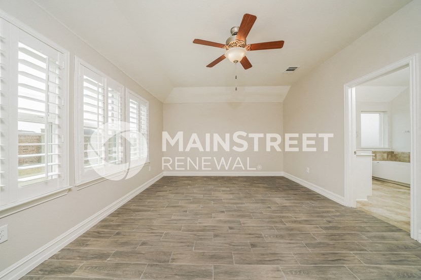 a living room with a large window and a ceiling fan