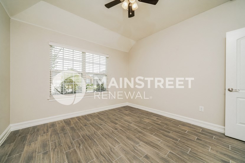 a bedroom with hardwood flooring and a window