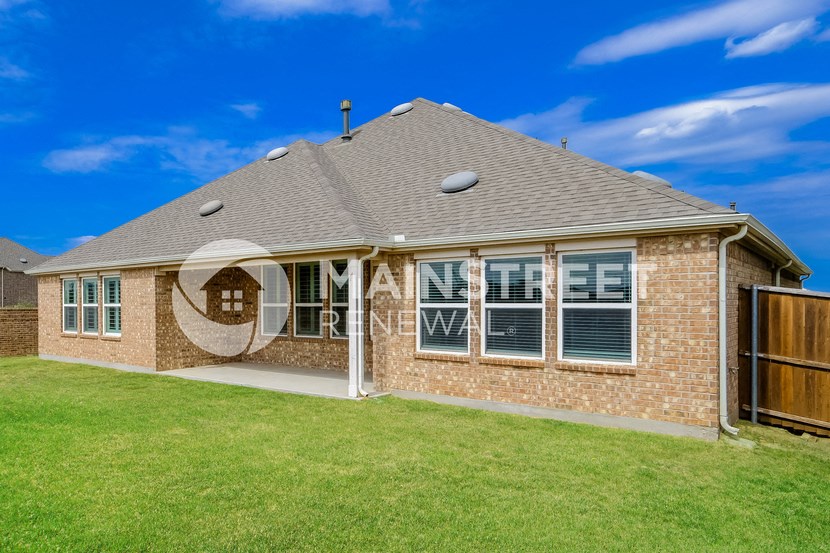 a brick house with a grass lawn and a blue sky