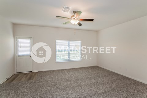 a living room with carpet and a ceiling fan