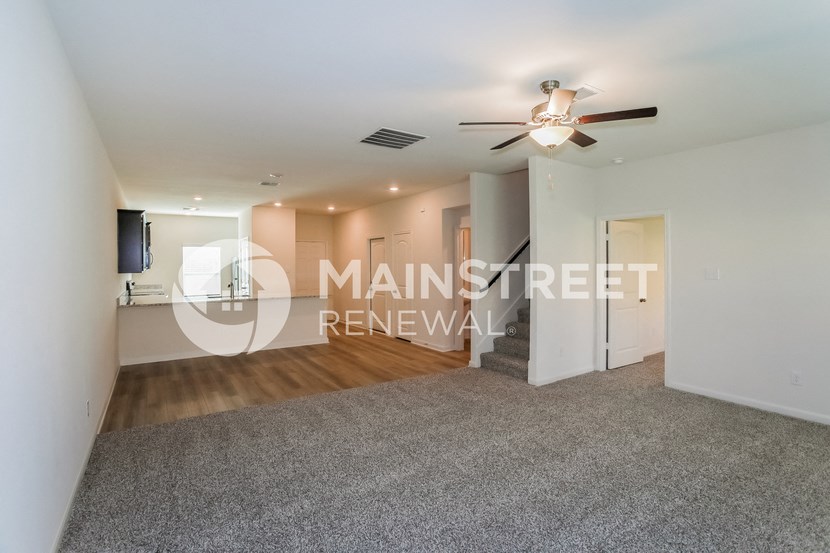 a renovated living room with a ceiling fan and a rug