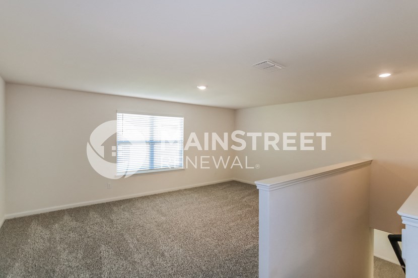 a upstairs living room with carpet and a window