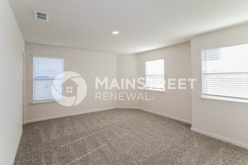 a living room with a carpet and two windows