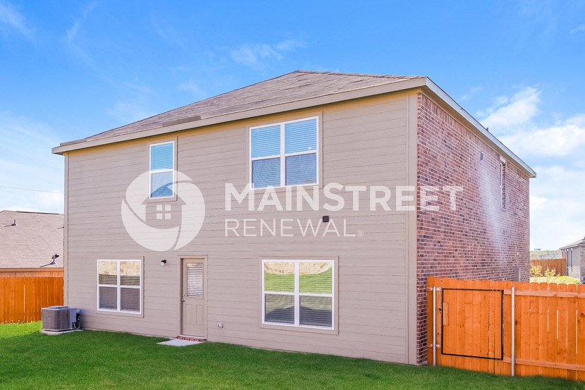 a small house with a yard in front of a wooden fence