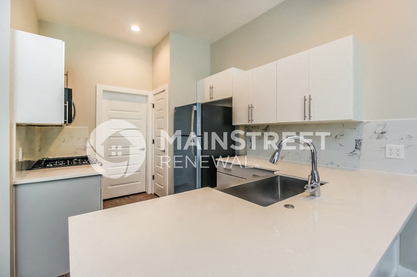 a renovated kitchen with white cabinets and stainless steel appliances