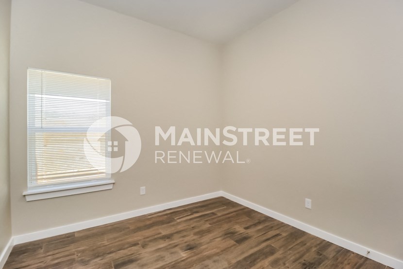 a bedroom with a window and a wooden floor