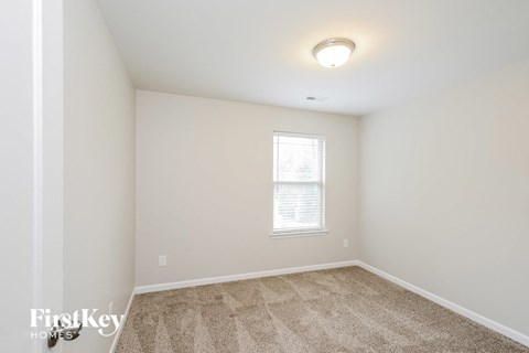 a bedroom with white walls and carpet and a window