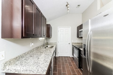 A kitchen with a granite counter top and stainless steel appliances.