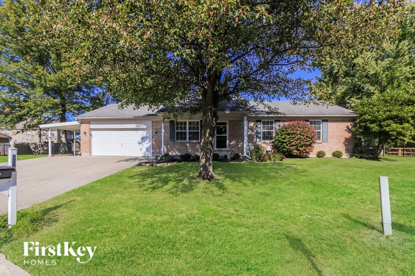 A tree in front of a house with a sign that says FirstKey Homes.