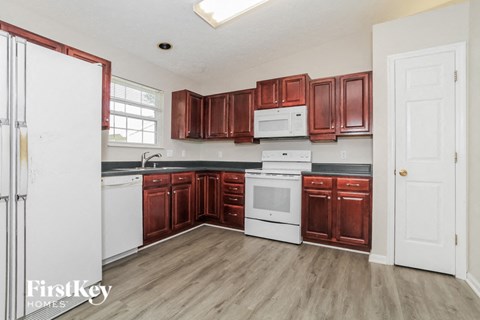 A kitchen with brown cabinets and a white fridge.